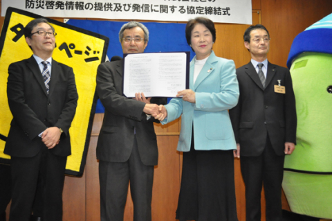 協定締結後、笑顔で握手を交わすＮＴＴタウンページの岡田社長（左から2人目）と吉村知事