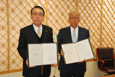 署名した協定書を披露する丸山市長（左）と千葉社長＝16日、酒田市役所
