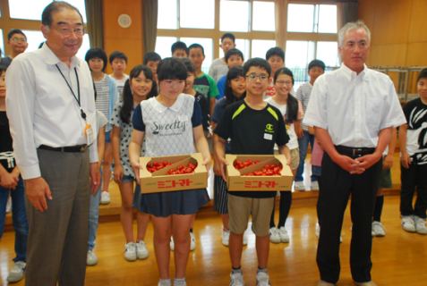 平田小で児童代表にトマトを贈った樋口代表（右端）