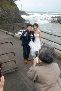 恋する灯台を背景に友人らから祝福を受ける海渡さんと瑞季さん