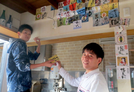 店舗内の装飾を行う山崎さん（右）。左は友人の畠山拓也さん＝18日午後