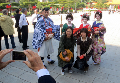 行く先々で人気となった酒田舞娘と山伏装束の佐藤さん。観光客に囲まれ、記念写真に納まった＝14日午後、台北市内の忠烈祠