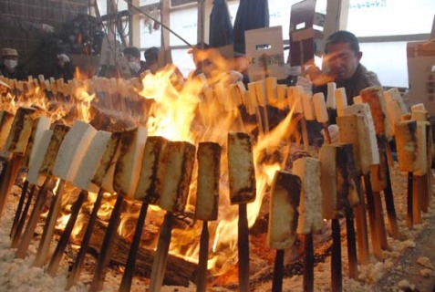 まきが燃え盛る大きないろりを囲んで伝統の「豆腐焼き」が行われた＝19日、下座の秋山さん方