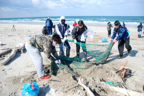 砂に埋もれた魚網も掘り起こして回収＝18日午前