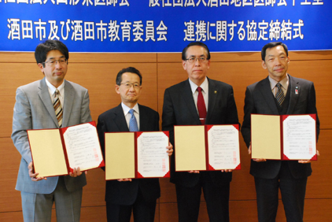 署名した協定書を披露する（左から）佐藤会長、中目会長、丸山市長、村上教育長