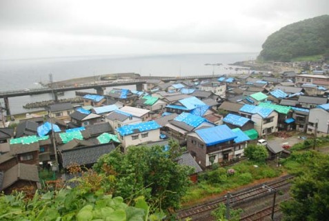 小岩川地区の多くの家屋屋根をブルーシートが覆う＝24日正午すぎ
