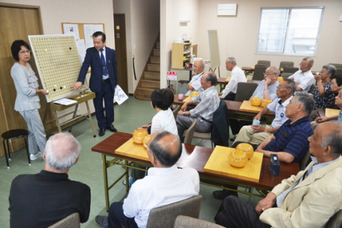 平本六段と小松四段のプロ棋士による大盤解説が行われ、会員たちが打ち方を学んだ