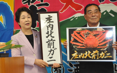 吉村知事（左）が庄内北前ガニのパネルを掲げ、本間組合長とブランド化への熱意を語った