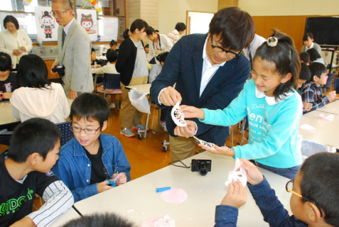 佐藤さんの指導で和紙を切り、傘福用の飾りを作る黒森小の子どもたち