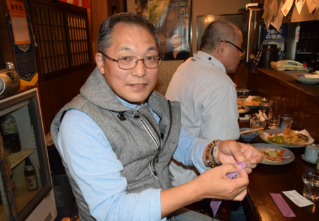 居酒屋で楽しみながら箸鶴を製作する伊藤さん（手前）