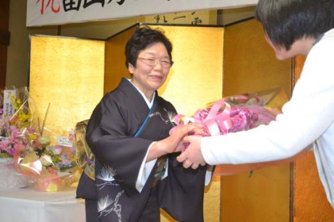 祝賀会でお孫さんから花束を贈られ、笑顔を見せる畠山さん