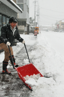 乾いた雪が降る中、雪かきに追われる市民＝7日午前9時ごろ、鶴岡市美原町
