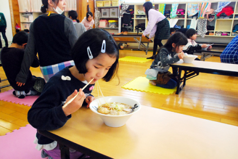 おいしそうにラーメンを食べる学童保育所の子どもたち＝30日、酒田市の浜田学区学童保育所