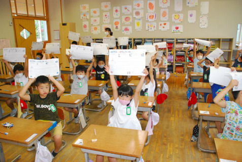 終業式後の教室で、「夏休み頑張るぞー」と生活表を掲げる子どもたち＝31日午前9時すぎ、鶴岡市の朝暘二小
