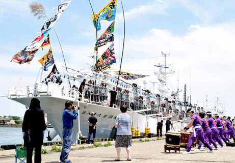 大漁旗で彩ったイカ釣り船が家族らに見送られ出航＝6日正午すぎ