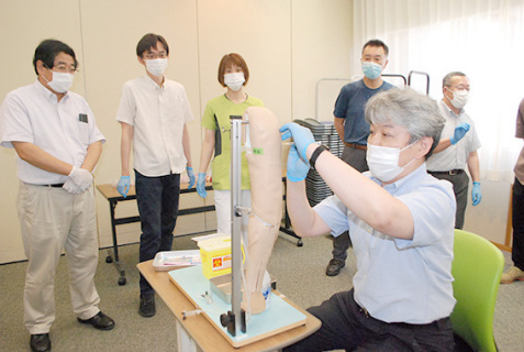 ダミー人形を使ってワクチン接種を実地で研修する歯科医師たち