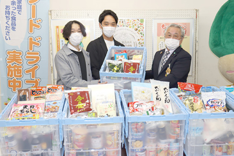 贈呈式で、貝沼部長（右）から食品を受け取る阿部代表（中央）と太田副代表