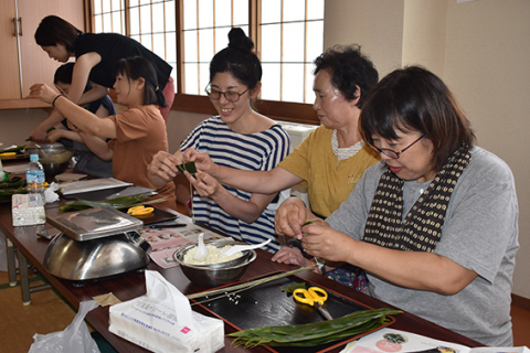 伊藤さん（右から2人目）から指導を受けながら笹巻を作る参加者