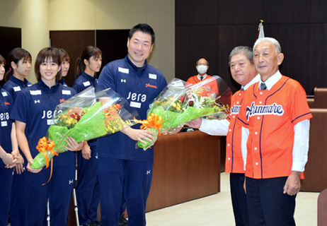 高橋議長（右）らから花束を贈られ笑顔の北原監督（中央）と木村主将（左）