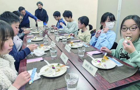 レンゲに載った料理を試食する小学生特別審査員