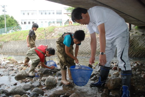 網で石の下などに隠れている生物を探る三瀬小の5年生たち＝降矢川