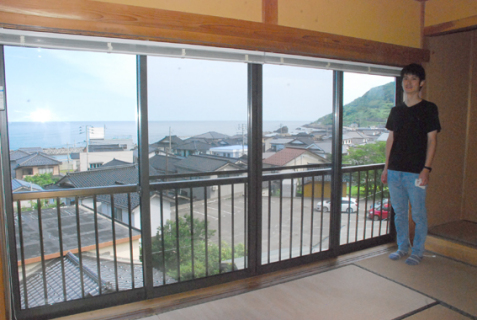 シェアハウス2階の居室。窓から海が見える。右は佐藤さん