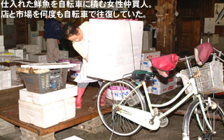 仕入れた鮮魚を自転車に積む女性仲買人。店と市場を何度も自転車で往復していた