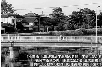 「小舞橋」は海坂藩城下北部の五間川下流に架かる＝鶴岡市街地の内川下流に架かる「三次郎橋」。奥に茂る数本の松は旧松原御殿（鶴岡市宝町）